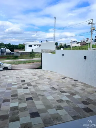 Área externa pavimentada com ladrilhos de pedra em frente à propriedade.