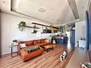 Sala de estar com sofá de couro marrom e piso de madeira.
