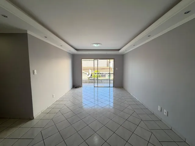 Ambiente interno de uma área ampla com piso de cerâmica e porta de vidro.