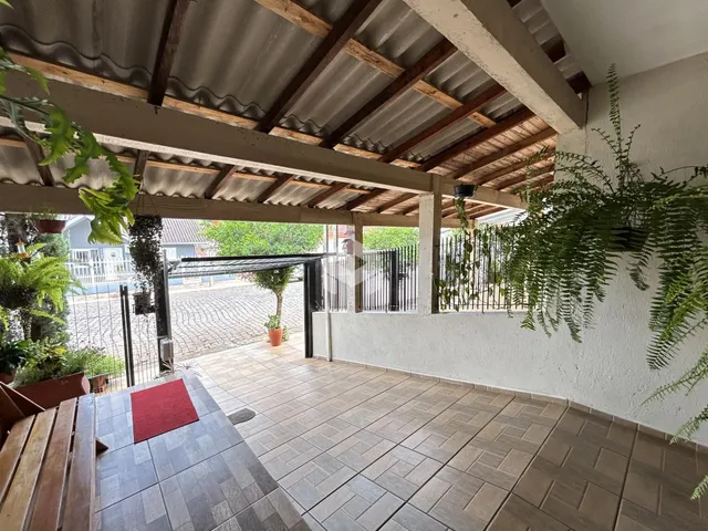 Vista de uma área externa coberta com piso de cerâmica e estrutura de madeira.