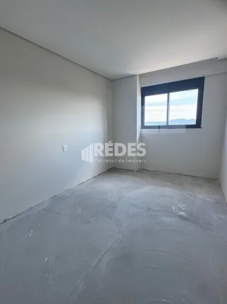 Foto de um cômodo interno com paredes brancas e piso de concreto cru.