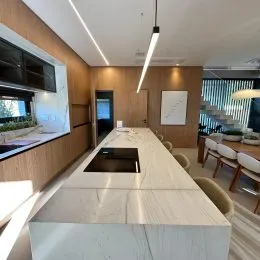 Vista de uma cozinha moderna com bancada de pedra clara e painéis de madeira.