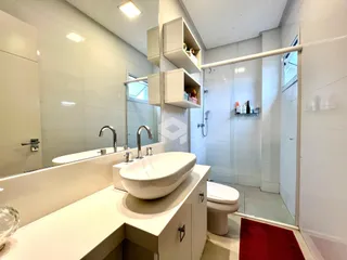 Banheiro moderno com box de vidro e bancada branca.