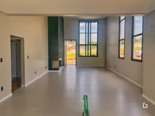 Interior de uma sala ampla com piso claro e paredes brancas.