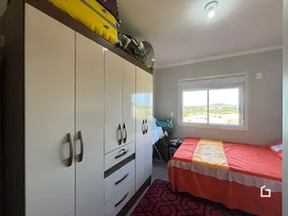 Quarto com armários brancos e cama na sala.