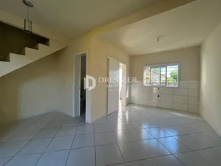 Interior de uma sala com piso de cerâmica e escadaria em um imóvel no Brasil.