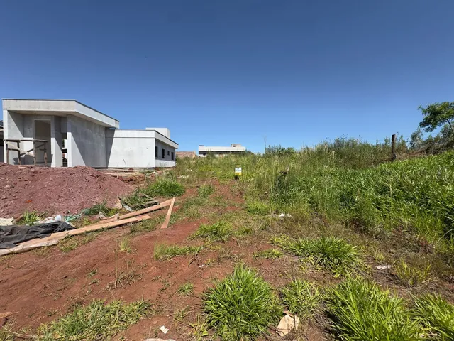 Vista externa de uma construção em andamento em um terreno com vegetação rasteira.
