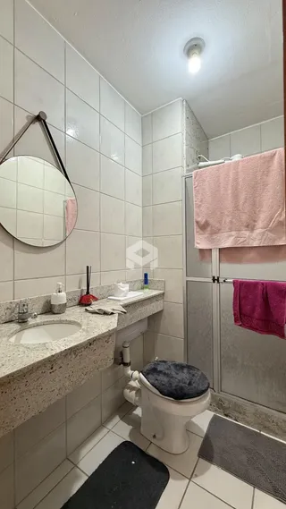 Banheiro com revestimento cerâmico branco e bancada de pedra.