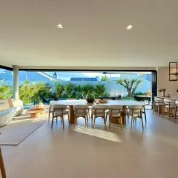 Sala de estar com grandes janelas que oferecem vista para a vegetação externa.