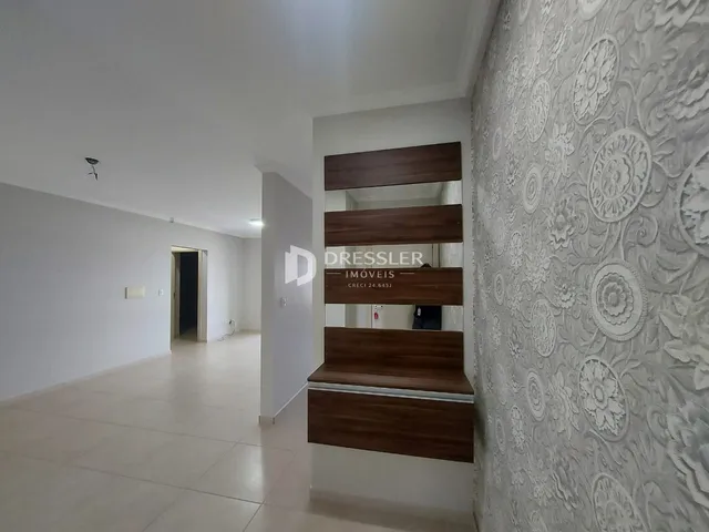 Hall da casa com paredes brancas e piso claro.