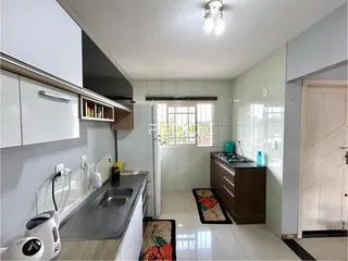 Foto interna de uma cozinha com revestimento de cerâmica e armários brancos.