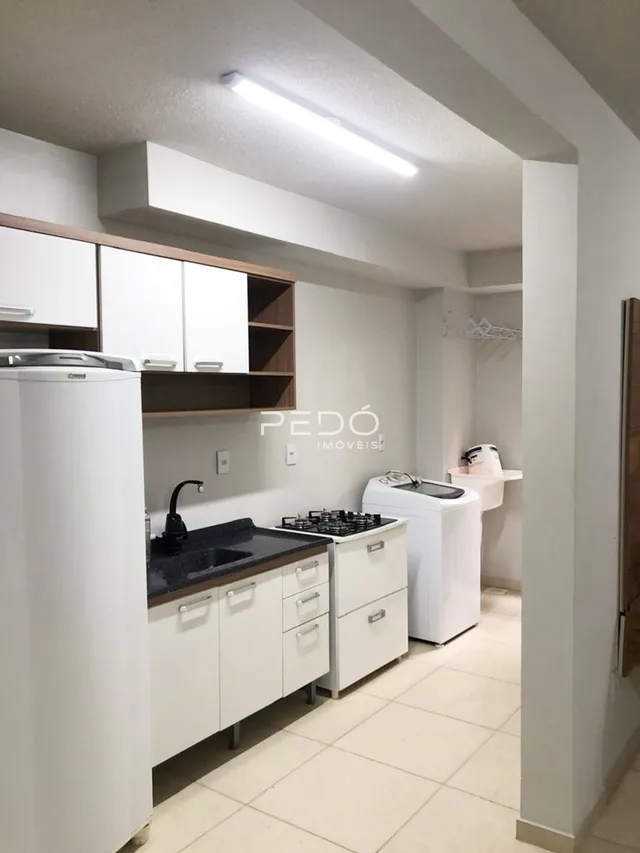 Vista interna de uma cozinha com armários brancos e piso claro.