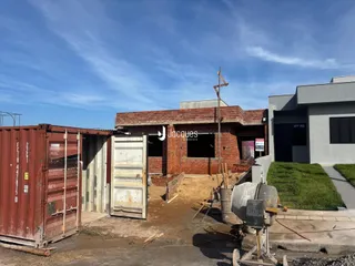 Vista externa de uma construção com contêineres ao fundo.