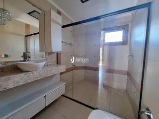 Interior de um banheiro com box de vidro e bancada de mármore.