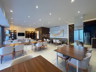 Ambiente interno de uma sala de jantar moderna com mesas de madeira e decoração contemporânea.