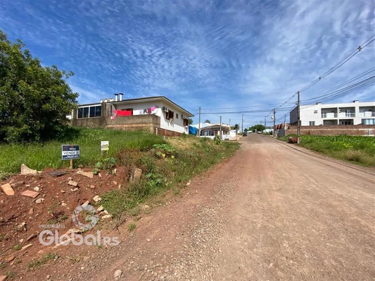 Vista de uma rua de terra em Lajeado, Brasil, com casas ao fundo.