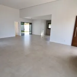 Vista interna de um ambiente amplo e claro com piso de cor neutra.