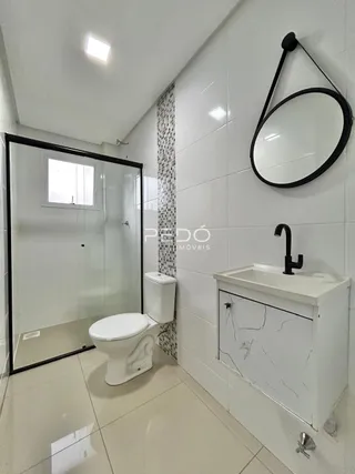 Foto de um banheiro com azulejos brancos e louças sanitárias.