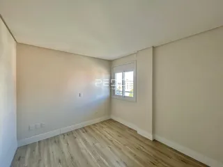Ambiente interno de uma sala com piso de madeira clara e paredes brancas.