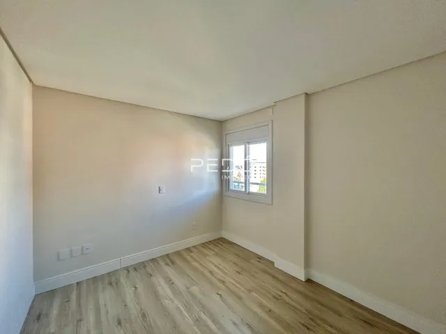 Ambiente interno de uma sala com piso de madeira clara e paredes brancas.