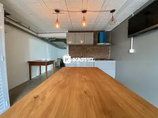 Foto interna de uma cozinha com armários e uma grande mesa de madeira.