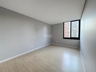 Imagem de um ambiente interno com paredes cinzas e piso de madeira clara.