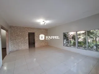 Uma sala ampla com piso de cerâmica e janelas voltadas para o exterior.