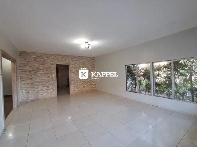 Uma sala ampla com piso de cerâmica e janelas voltadas para o exterior.