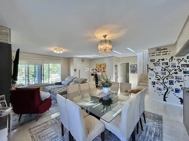 Sala de estar com mesa de jantar e grandes janelas em um imóvel no Brasil.