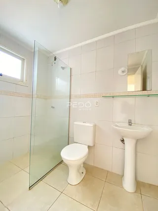 Foto de um banheiro com revestimento cerâmico e box de vidro.