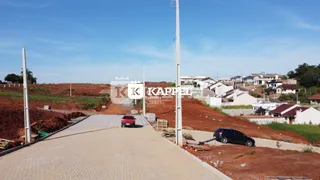 Foto da entrada de uma propriedade com uma estrada pavimentada e terreno baldio ao redor.