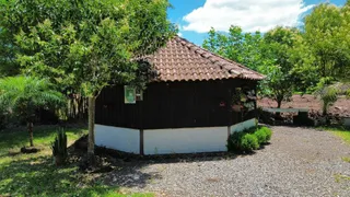 Estrutura rústica de madeira com telhado de telhas no exterior em uma área verde.