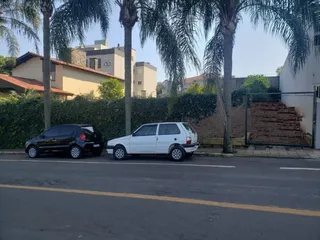 Vista externa de uma rua residencial em Lajeado, Brasil, com veículos estacionados e vegetação.