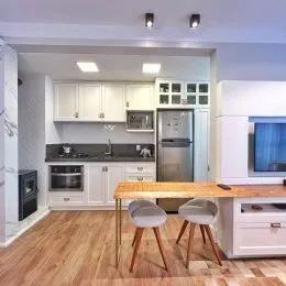 Cozinha com armários brancos e piso de madeira clara.