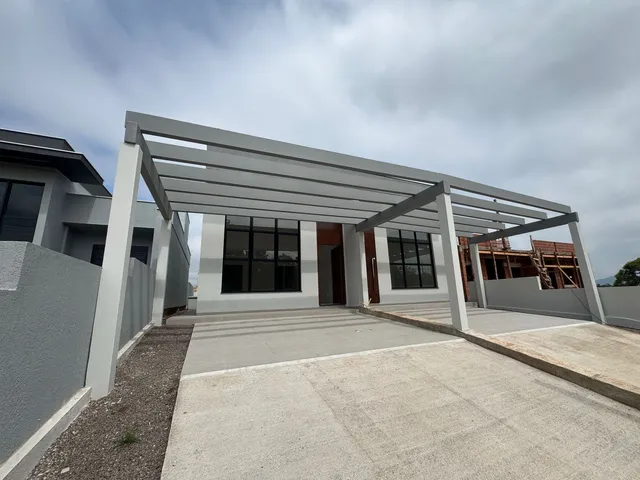 Fachada de uma casa moderna com estrutura de cobertura em concreto e madeira.