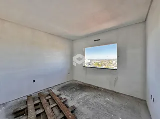 Interior de um cômodo vazio com paredes brancas e piso de concreto.