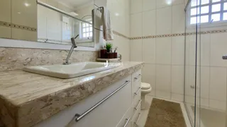 Banheiro com revestimento de cerâmica e bancada de mármore.