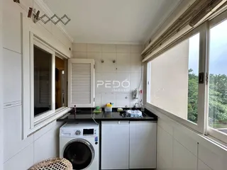 Vista da cozinha com máquina de lavar roupa e janela em imóvel no Brasil.
