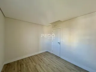 Imagem de um ambiente interno com piso de madeira clara e paredes brancas.