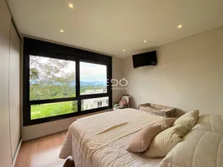 Quarto com grande janela e vista para a paisagem.