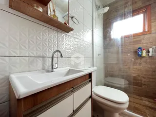 Foto de um banheiro com revestimento de azulejos brancos e box de vidro.