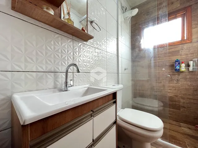 Foto de um banheiro com revestimento de azulejos brancos e box de vidro.