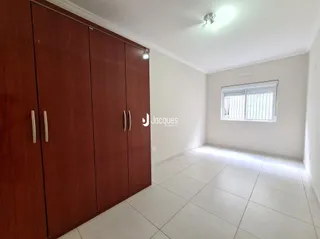 Quarto com armário de madeira e piso de cerâmica claro.