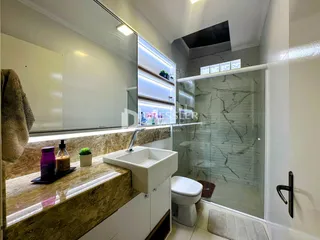 Foto de um banheiro moderno com box de vidro e bancada de mármore.