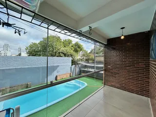 Vista da sala com vista para uma piscina externa através de grandes janelas de vidro.
