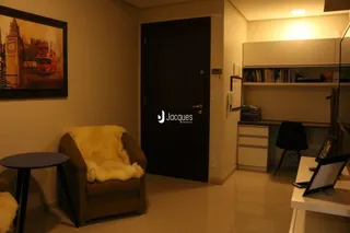 Ambiente interno de uma sala com uma poltrona e parede decorada.