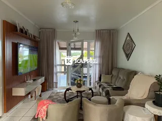 Sala de estar com sofá e televisão em um ambiente claro com portas de vidro.
