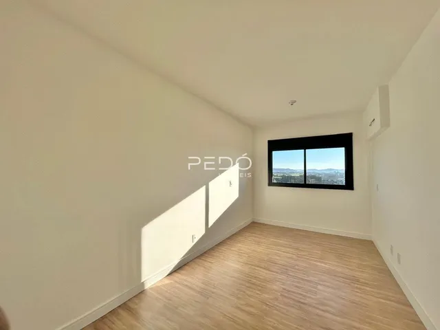 Uma sala de estar com piso de madeira e janela de grande porte.
