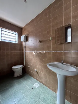 Banheiro com piso cerâmico e paredes de azulejo marrom.
