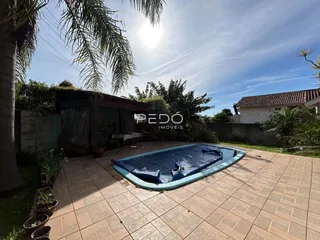 Vista externa de um pátio com piscina inflável e vegetação ao ar livre.